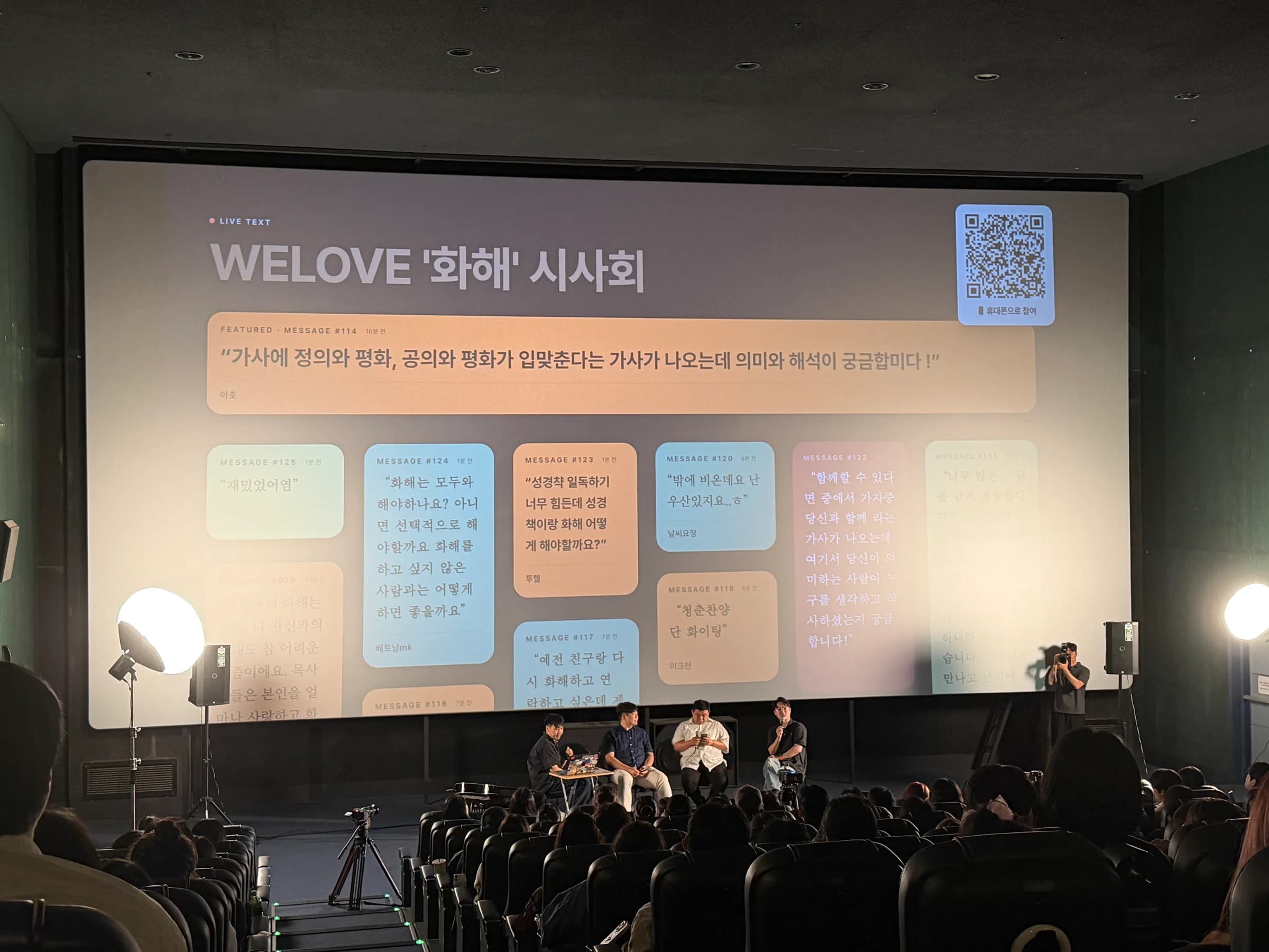 WELOVE 화해 시사회에서 QR과 관객 질문, 패널이 함께 보이는 무대 전경